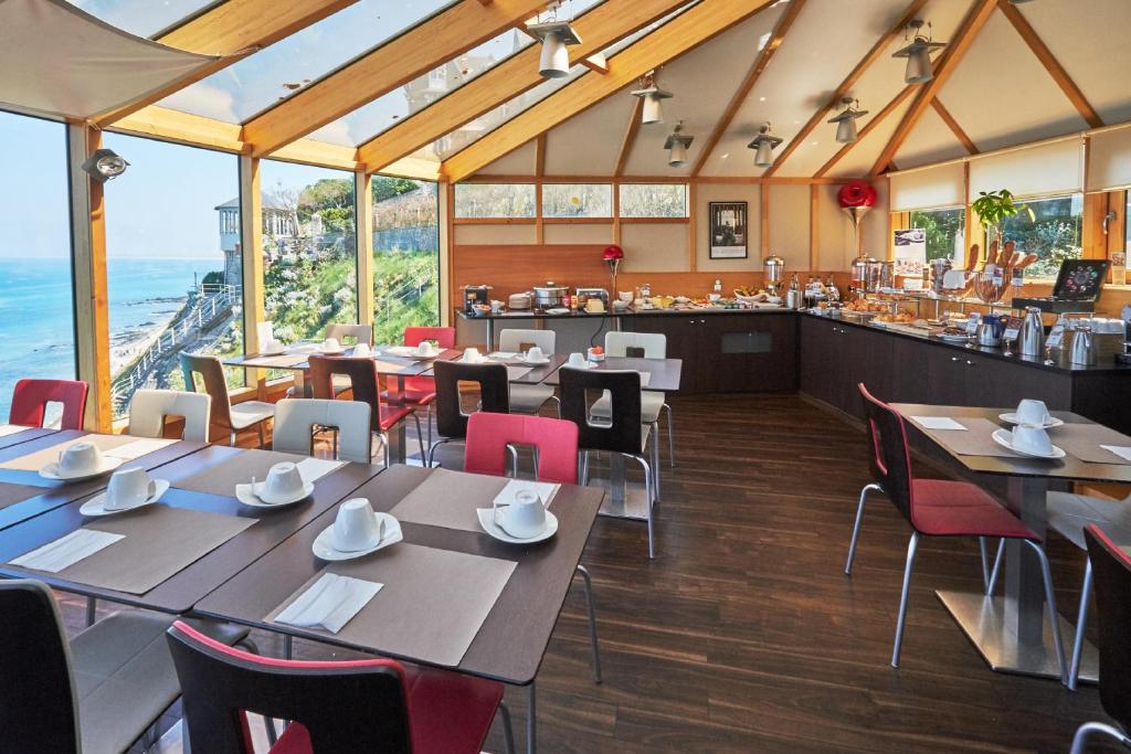 a restaurant with tables and chairs and a bar at Mercure Granville Le Grand Large in Granville