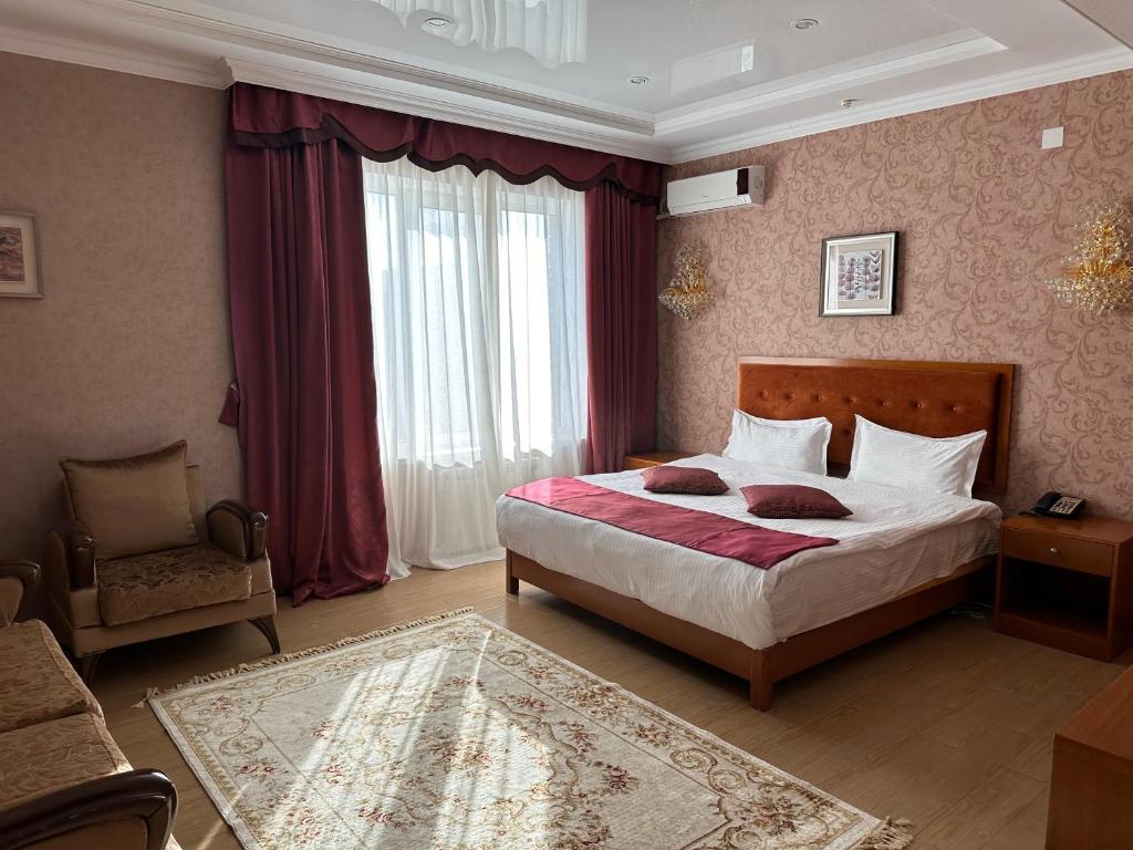 um quarto com uma cama grande e uma cadeira em Royal em Aqtöbe
