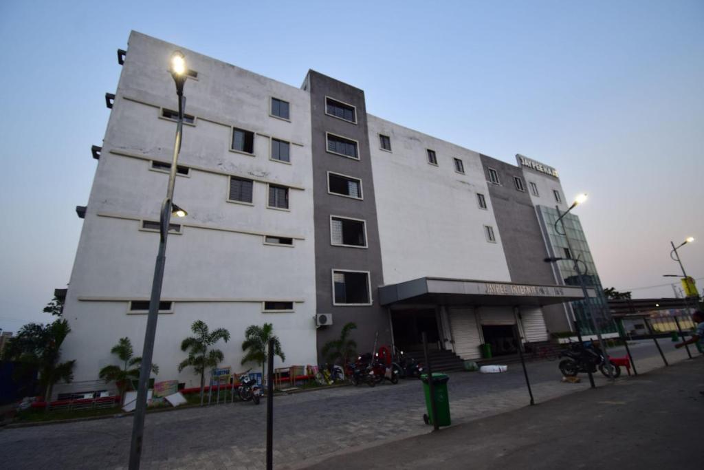 wysoki biały budynek z światłem ulicznym przed nim w obiekcie OYO Flagship Bengal Inn w mieście Sānkrāil