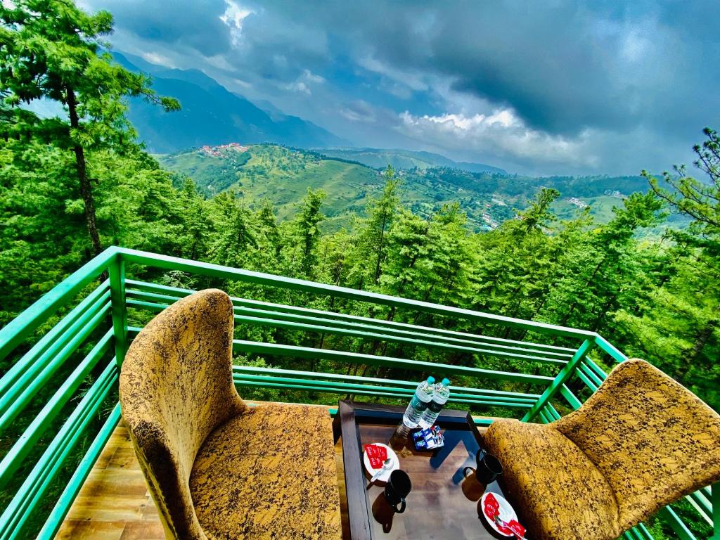 2 sillas y mesa en un balcón con vistas en Nature Mountain Valley View Resort -- A Four Star Luxury Resort en Shimla