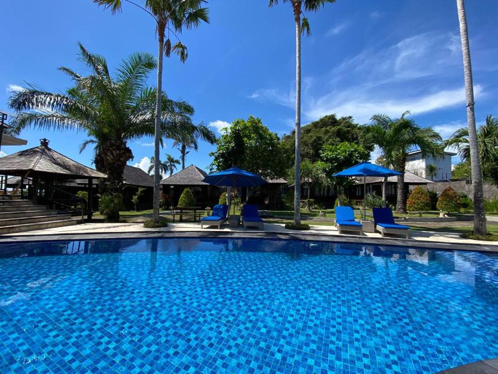 a large swimming pool with blue chairs and umbrellas at Balangan Surf Resort in Jimbaran