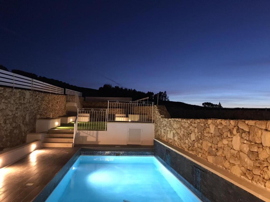 a villa with a swimming pool and a stone wall at Charming and Tranquil House in Għasri