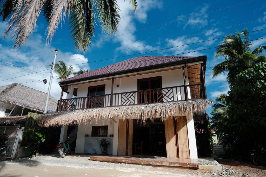 a house with a balcony and palm trees at Copacabana Siargao in General Luna