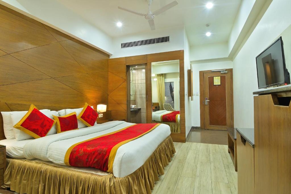 a bedroom with a large bed and a flat screen tv at Hotel Hari Piorko Grand - New Delhi Railway Station in New Delhi