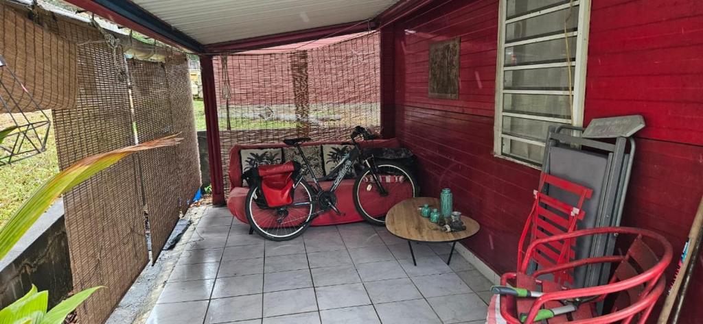 ein Fahrrad auf einer Veranda mit einem Tisch und Stühlen geparkt in der Unterkunft SWEET SPOT in Saint-Laurent du Maroni