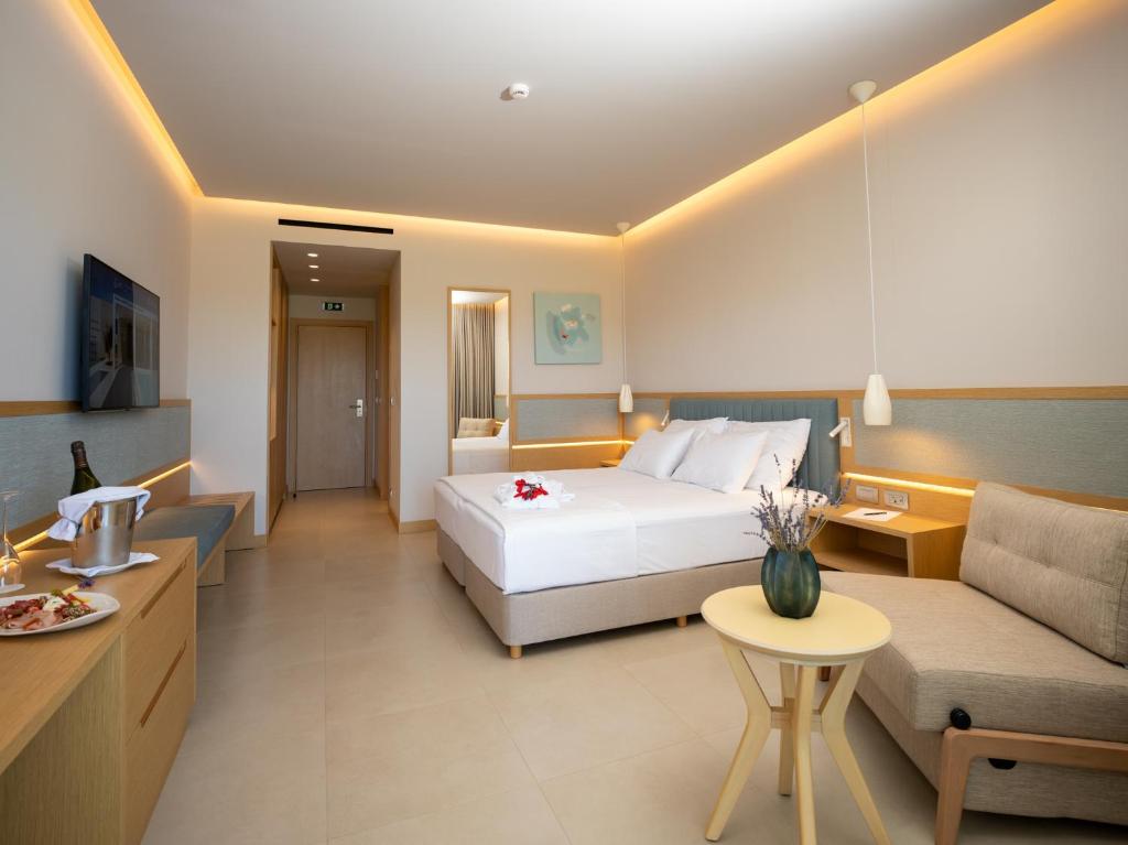 a hotel room with a bed and a couch at Ammoa Luxury Hotel & Spa Resort in Nikiti