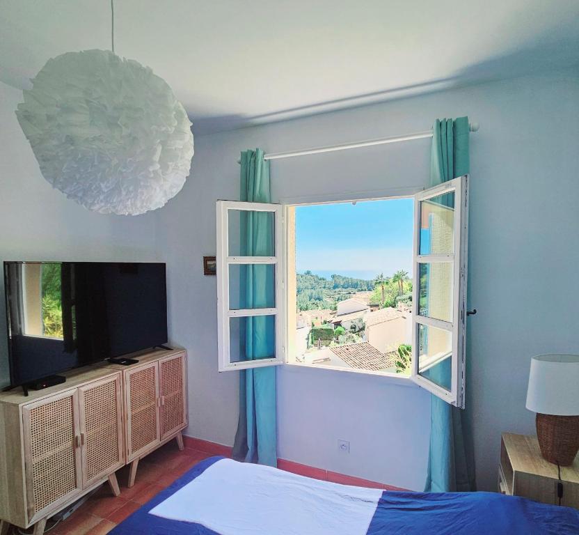 een slaapkamer met een raam en een televisie bij TRES BEL APPARTEMENT VUE MER - Piscine - Tennis et Golf in Saint-Cyr-sur-Mer