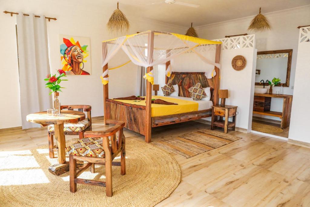 een slaapkamer met een hemelbed en een tafel en stoelen bij Z-Lodge Zanzibar in Kiwengwa