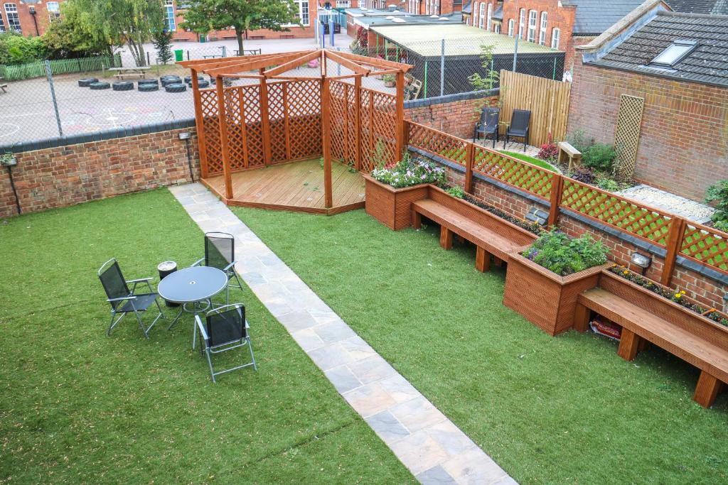 un jardín con mesa, sillas y una valla en Oscar Lodge en Northampton