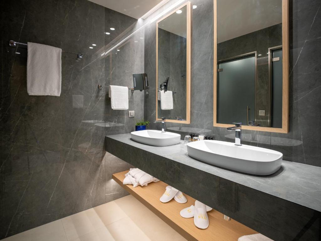 a bathroom with two sinks and a shower at Ammoa Luxury Hotel & Spa Resort in Nikiti