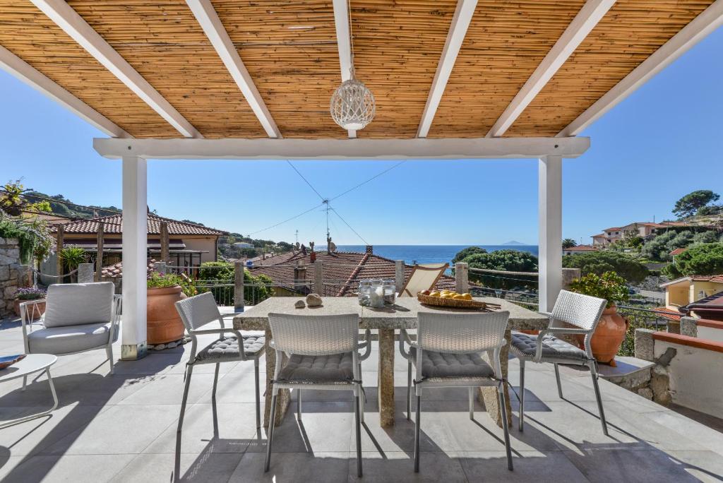 un patio con tavolo, sedie e vista sull'oceano di Villetta Melete a Campo nell'Elba