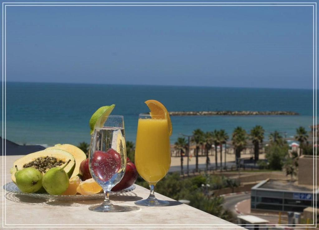 Bugrashov Beach 88 Hotel And Spa في تل أبيب: صينية من الفاكهة والمشروبات على طاولة بالقرب من الشاطئ