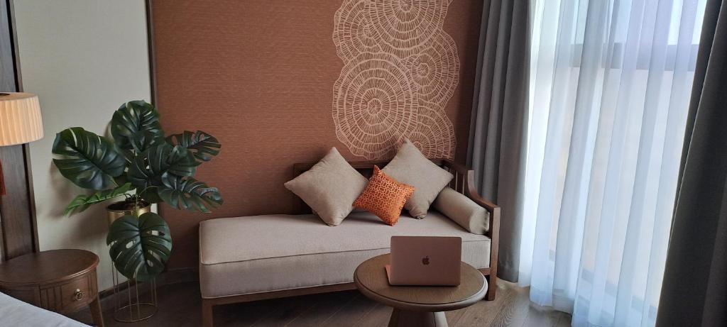 a living room with a couch with a laptop on a table at Apec Mandala Mui Ne Beach Studio in Ấp Thiẹn Ái