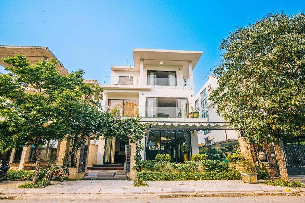 a white house with trees in front of it at Villa FLC Sầm Sơn Thanh Hoá in Sầm Sơn