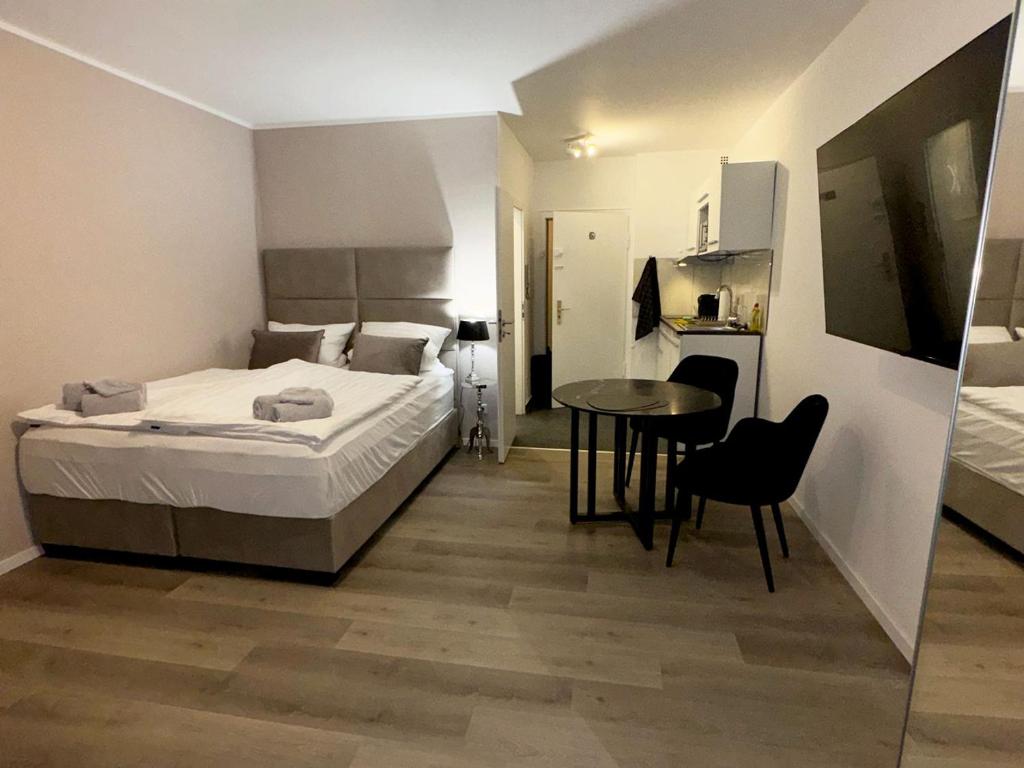 a bedroom with a bed and a table and a kitchen at City Spot Zimmer24Frei in Köln in Cologne