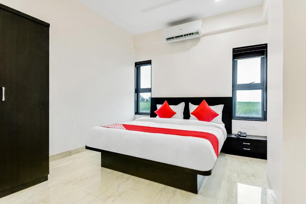 1 dormitorio con 1 cama grande con almohadas rojas en Flagship V&s Hotel, en Pimpalgaon