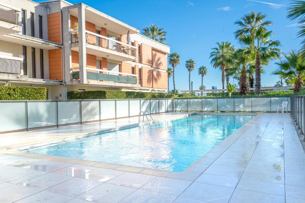 une piscine devant un immeuble avec des palmiers dans l'établissement Royal Cap, à Villeneuve-Loubet