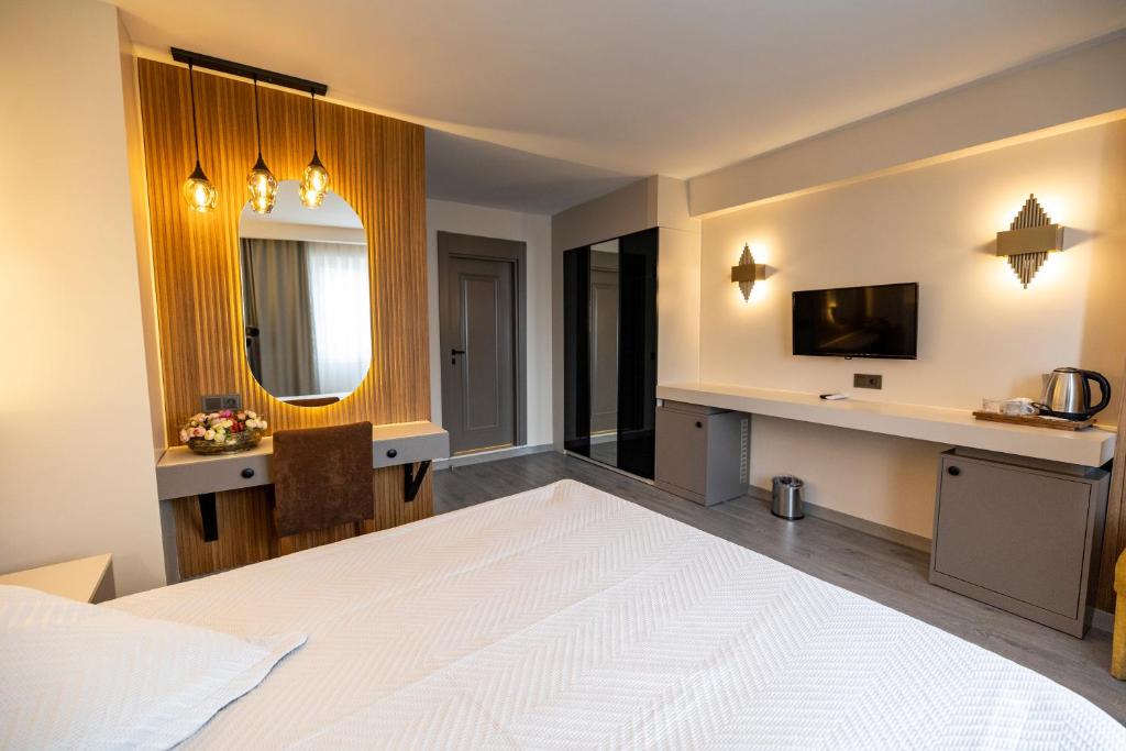 a bedroom with a large white bed and a desk at Aktas Hotel in Mersin