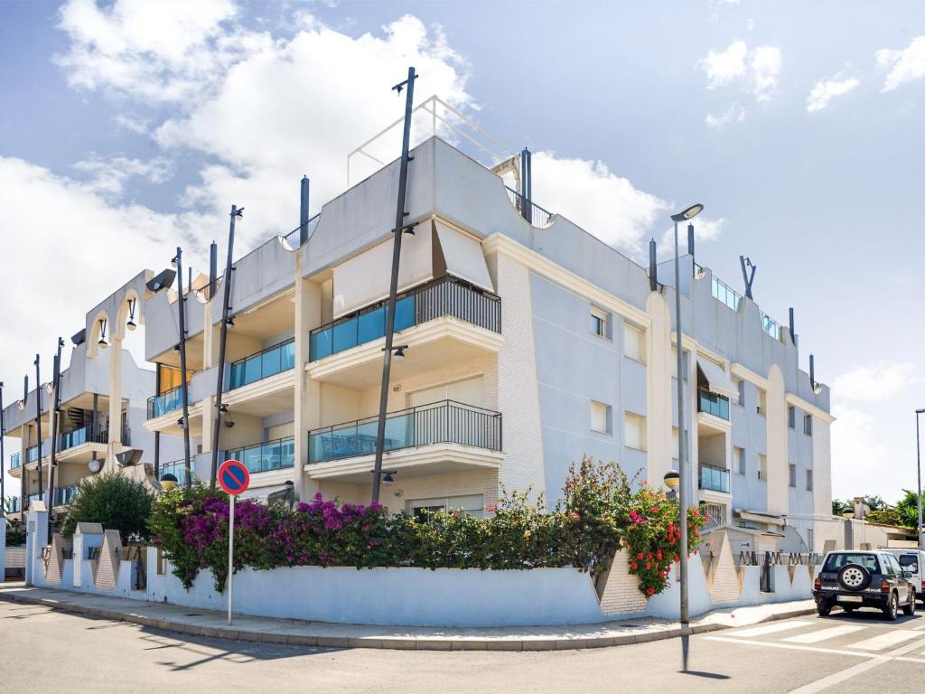 um edifício branco com flores num parque de estacionamento em Comfortable apartment at only 100 metres from the sea em Deltebre