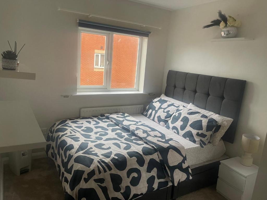 a bed with a black and white comforter and a window at 231 Senwick drive in Wellingborough