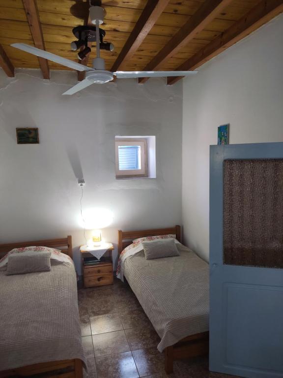 a bedroom with two beds and a ceiling at Calliope's house in Lipsoi