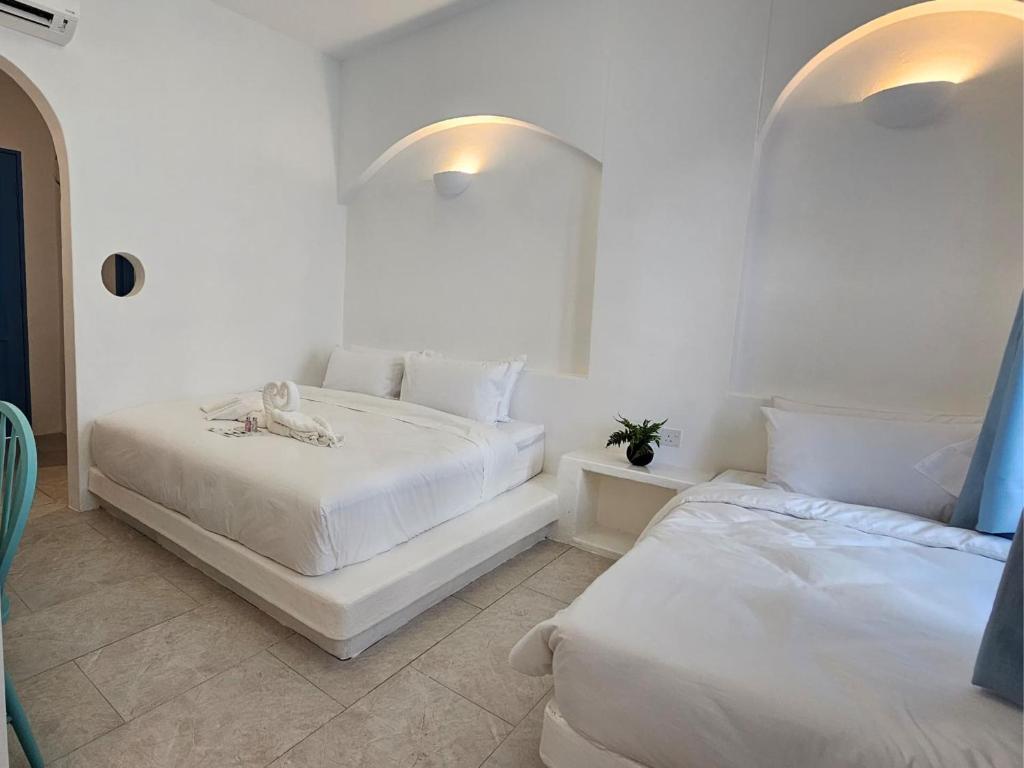 Habitación blanca con 2 camas y espejo. en Ipoh Santorini Hideaway - Hotel Inspired en Ipoh