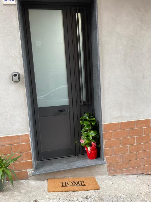 una alfombra de bienvenida frente a una puerta con una planta en La Marchesina House, en Misterbianco
