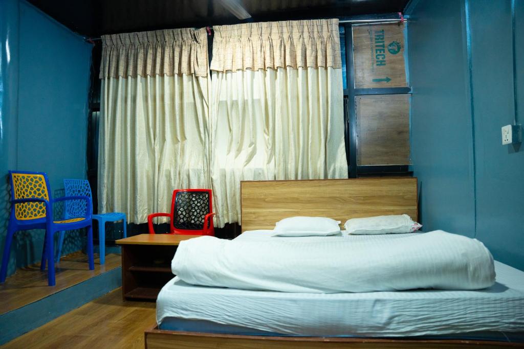 a bedroom with a bed with blue walls and chairs at Universal Hotel & Lodge - Gorkha in Gorkhā