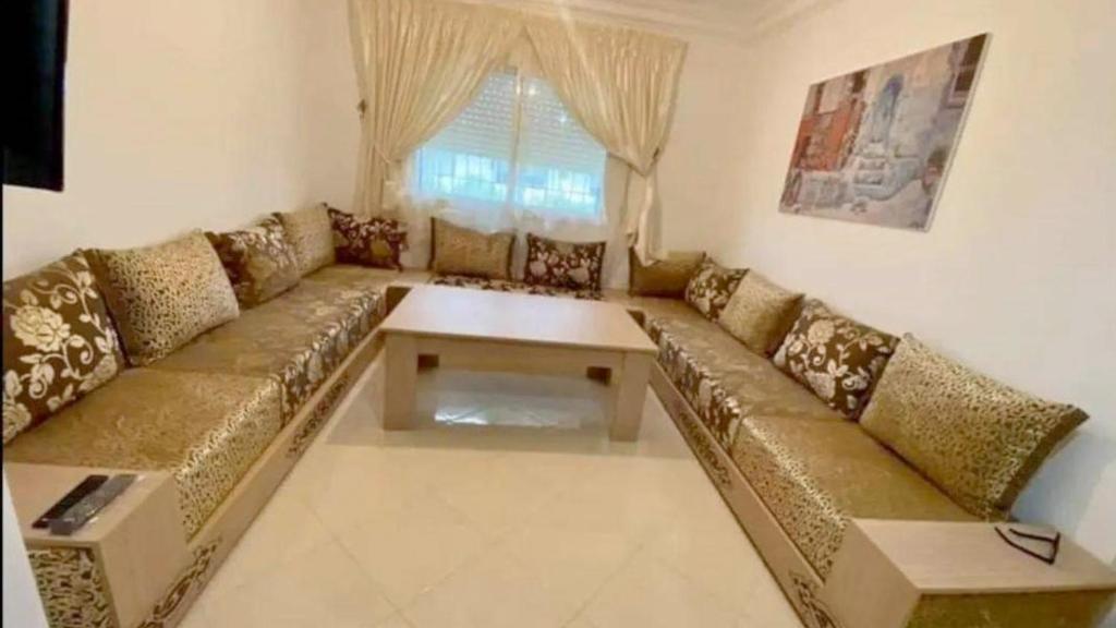 uma sala de estar com um sofá e uma mesa em APPARTEMENT DE LUXE CENTRE VILLE em Kenitra