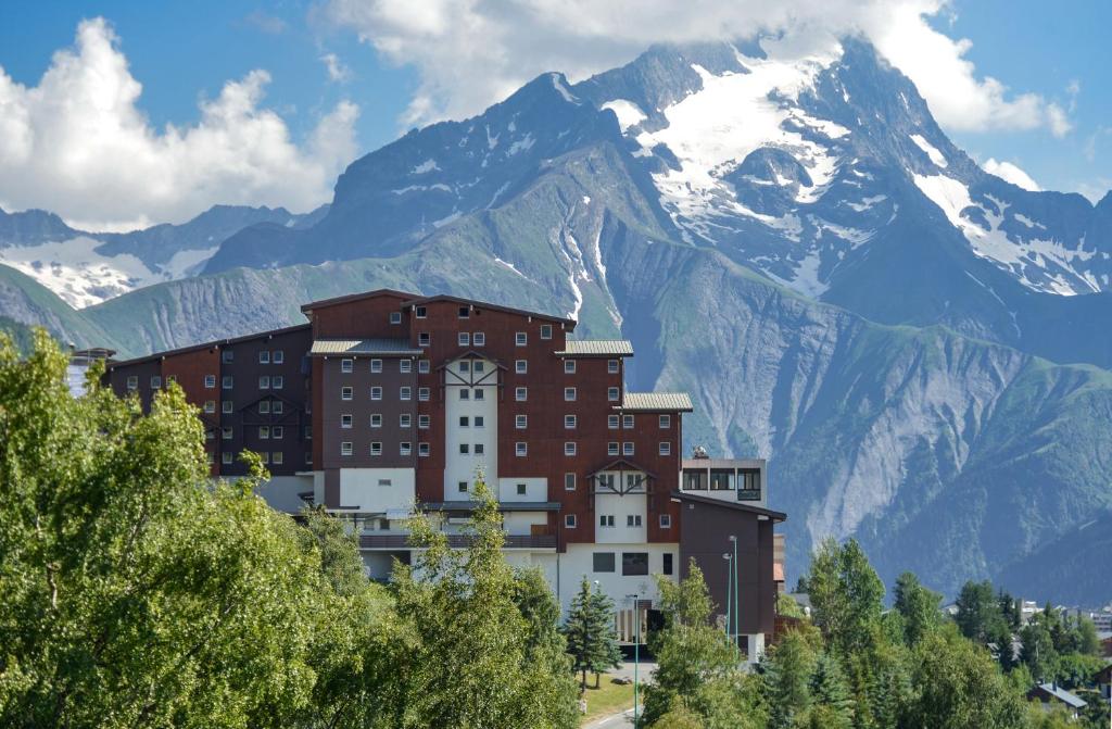 un edificio con una montaña en el fondo en Villages Clubs du Soleil - LES 2 ALPES en Les Deux Alpes