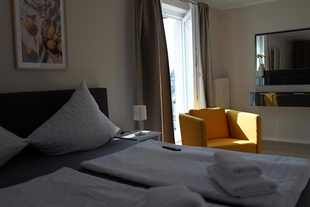 ヒルデスハイムにあるHotel Milanoのベッドと黄色い椅子が備わるホテルルームです。
