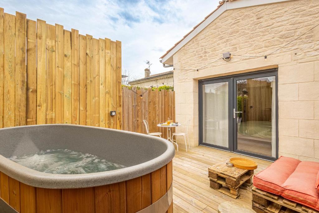 uma banheira num pátio com uma cerca de madeira em Chambres d'hôtes Le Studio Bordelais avec bain nordique em Mérignac