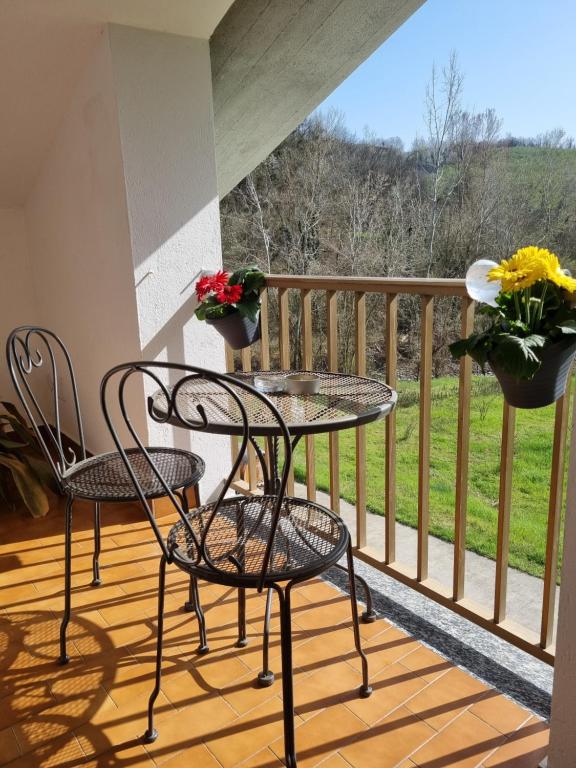 dwa krzesła i stół na balkonie z kwiatami w obiekcie Ospitalità Agricola di Langa Alloggio Mansardato Vacanze w mieście Sinio