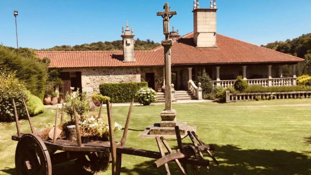 una iglesia con una cruz y una carretilla en el patio en Pazo de Bendoiro, en Bendoiro