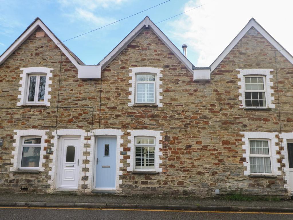 uma casa de tijolos com portas e janelas brancas em Riversdale Cottage em Wadebridge