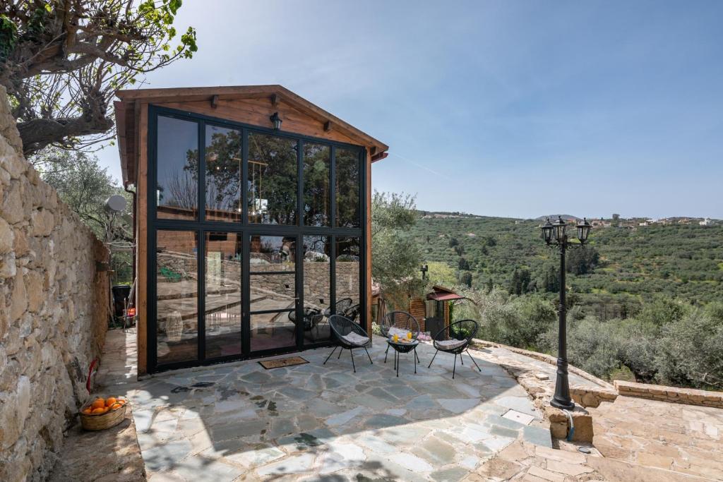 a glass house with a table and chairs on a patio at Wooden House Apts - Between Balos & Elafonissi in Kaláthenai