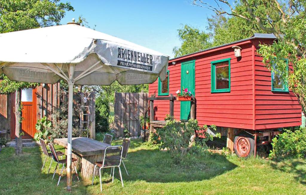 a red and green tiny house with a table and an umbrella at 1 Bedroom Cozy stacaravan In Warthe in Warthe