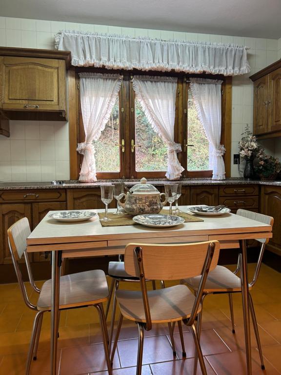 una cocina con una mesa con 4 sillas y una ventana en Del Valle 3, en Cudillero