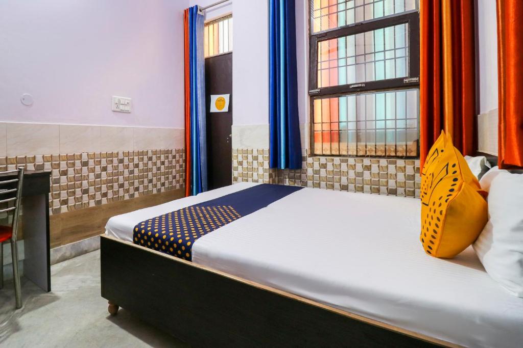 a bedroom with a bed with orange and blue curtains at SPOT ON APNA LOUDGE in Ghaziabad