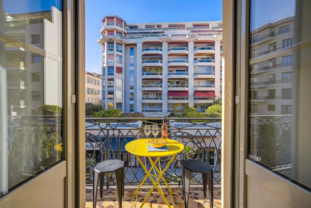 d'un balcon avec une table jaune et deux chaises. dans l'établissement Maison Bianchi - Hôtel des Postes, à Nice