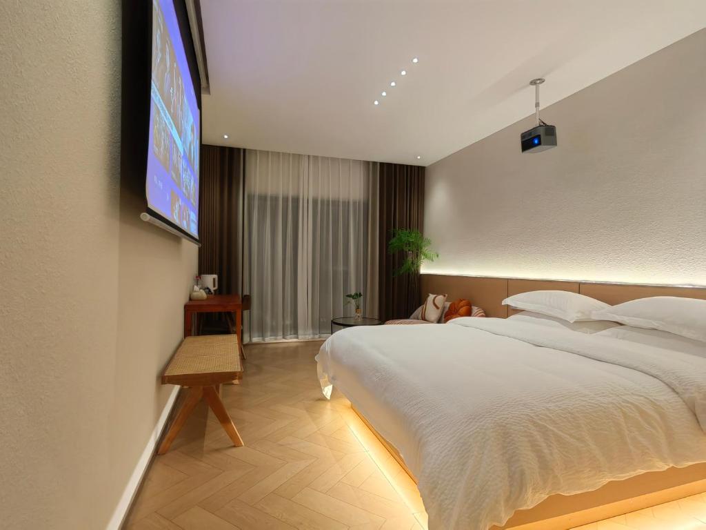 a bedroom with a large bed with a tv on the wall at Flower Whisperer Homestay Tianmenshan Store free airport and station pick-up in Zhangjiajie