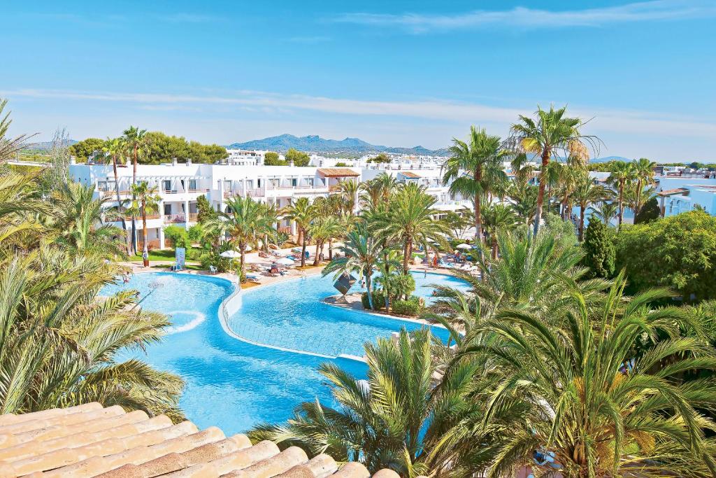 an aerial view of a resort pool with palm trees at Hotel Calimera Fido Gardens in Cala d´Or