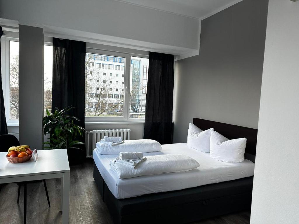 1 dormitorio con 2 camas, mesa y ventanas en Ootel.com en Berlín