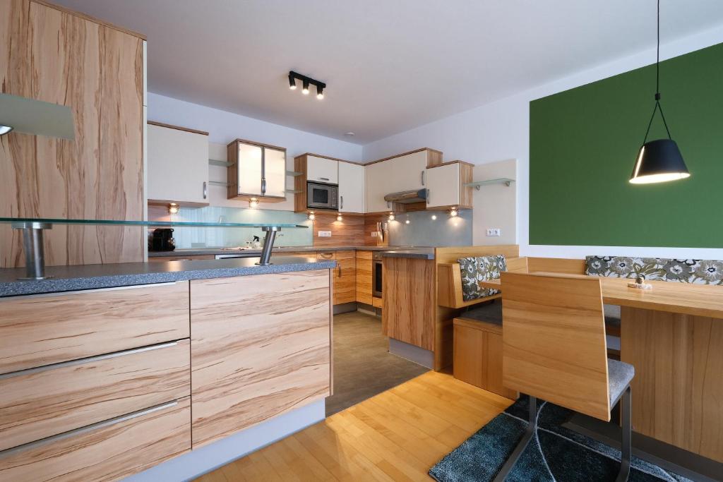 a kitchen with wooden cabinets and a green wall at See-Apartments Kärntnerhof in Weissensee