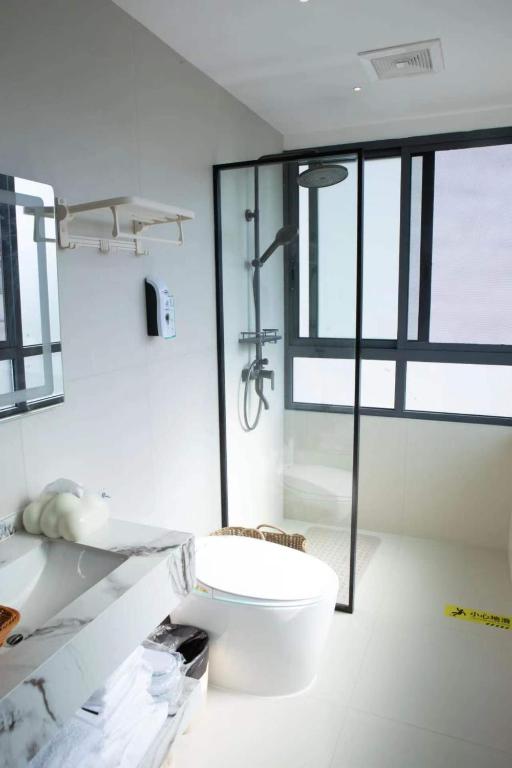 a bathroom with a toilet and a glass shower at Flower Whisperer Homestay Tianmenshan Store free airport and station pick-up in Zhangjiajie