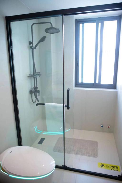 a glass shower in a bathroom with a toilet at Flower Whisperer Homestay Tianmenshan Store free airport and station pick-up in Zhangjiajie
