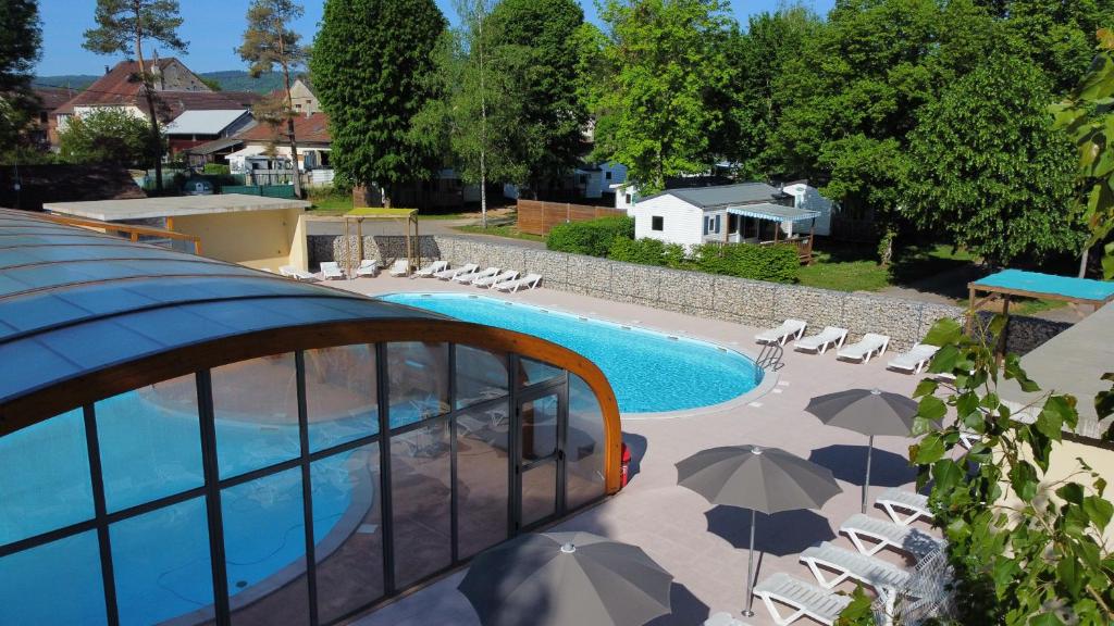 a swimming pool with chairs and umbrellas next to it at camping les pêcheurs in Pont-de-Poitte