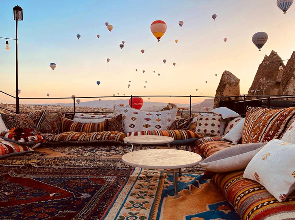 a room with couches and hot air balloons in the sky at Dervish Cave House & Restaurant in Goreme