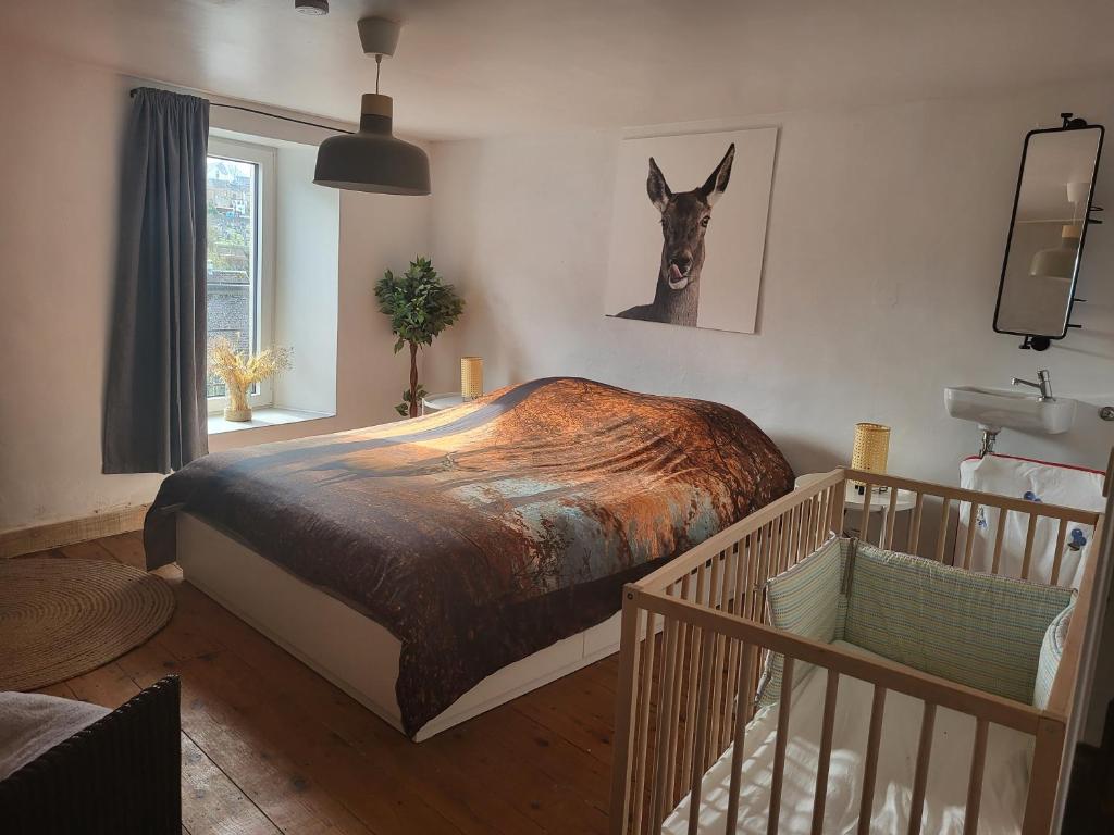 - une chambre avec un grand lit et une couverture brune dans l'établissement Le Grand Cerf gîte citadin, à Saint-Hubert