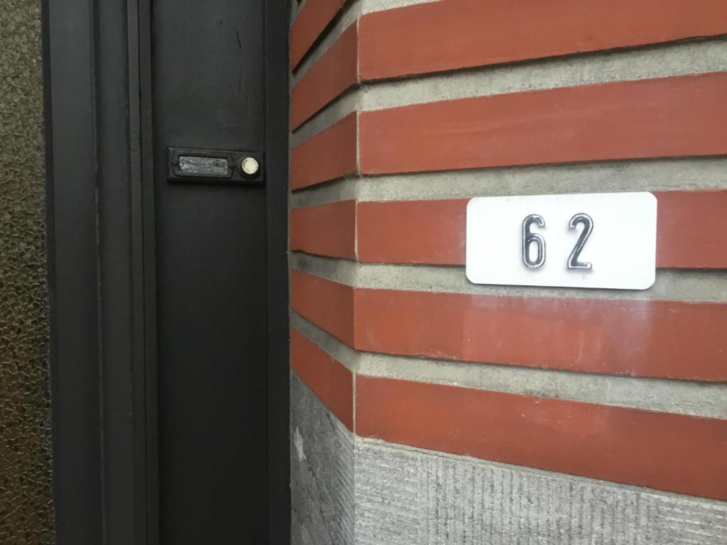 un cartello bianco su un muro di mattoni vicino a una porta di Londerzeel Logies a Londerzeel